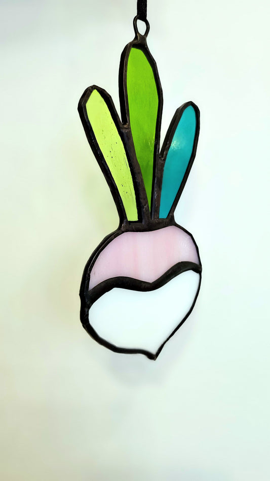 Pink and white stained glass turnip hanging on a branch
Suspension navet en verre, rose et blanc, suspendue à une branche