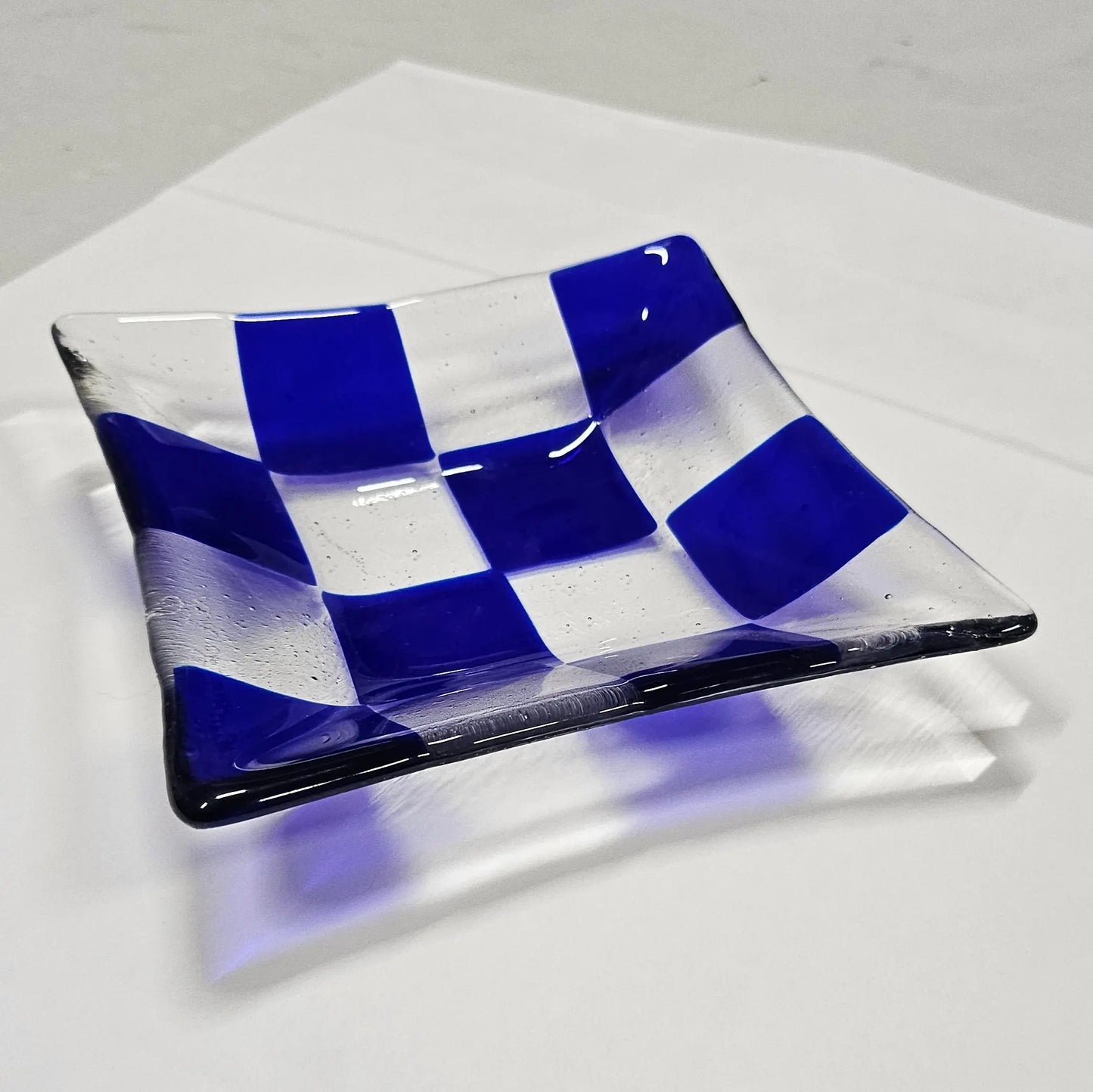 Blue and transparent fused glass tray with a checkered pattern, perfect for organizing small items while adding a decorative touch.
Vide-poches en verre fusionné fusing avec un motif de carreaux, idéal pour organiser vos petits objets tout en apportant une touche déco.
