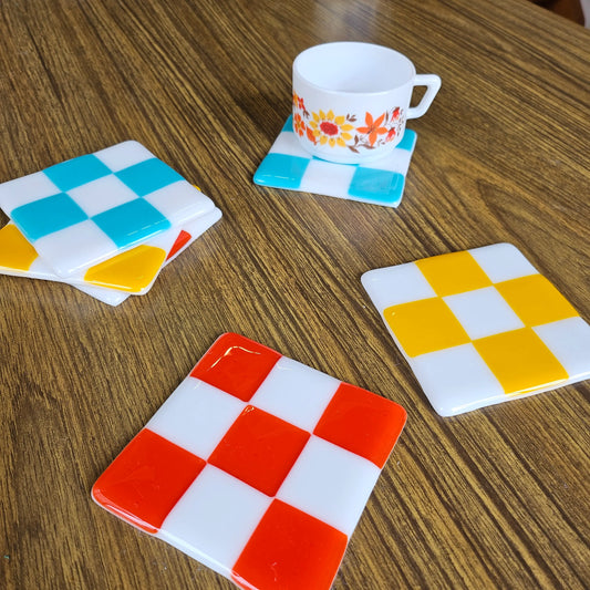 Set of six fused glass coasters featuring checkered patterns in red and white, yellow and white, and blue and white. A bright and colorful handcrafted design, perfect for adding a modern and elegant touch to your table.

 Ensemble de six dessous de verre en verre fusionné, aux motifs à carreaux rouge et blanc, jaune et blanc, et bleu et blanc. Un design artisanal lumineux et coloré, idéal pour apporter une touche élégante et moderne à votre table.