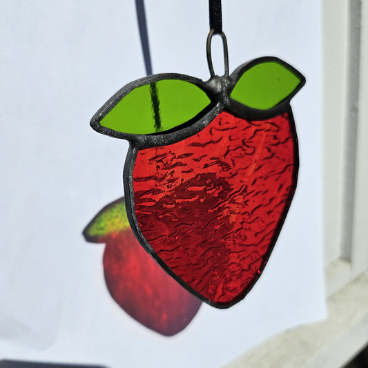 Vibrant stained glass strawberry suncatcher. Unique handmade décor piece for cheerful interiors.
Suspension en vitrail en forme de fraise, artisanale et colorée. Déco unique pour illuminer votre maison.